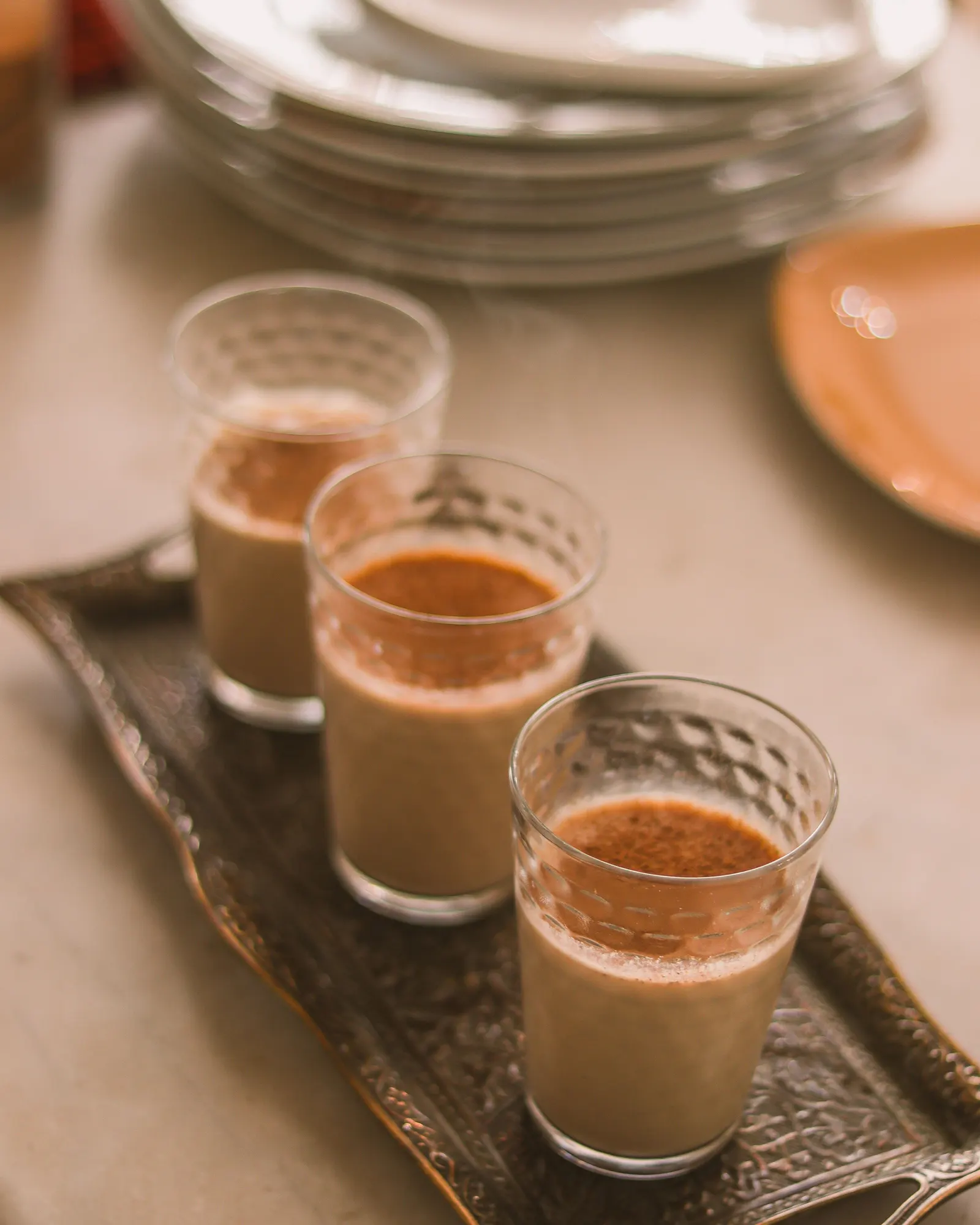 Temporary concept image of glasses of chai on a tray in warm afternoon light; not property photography.