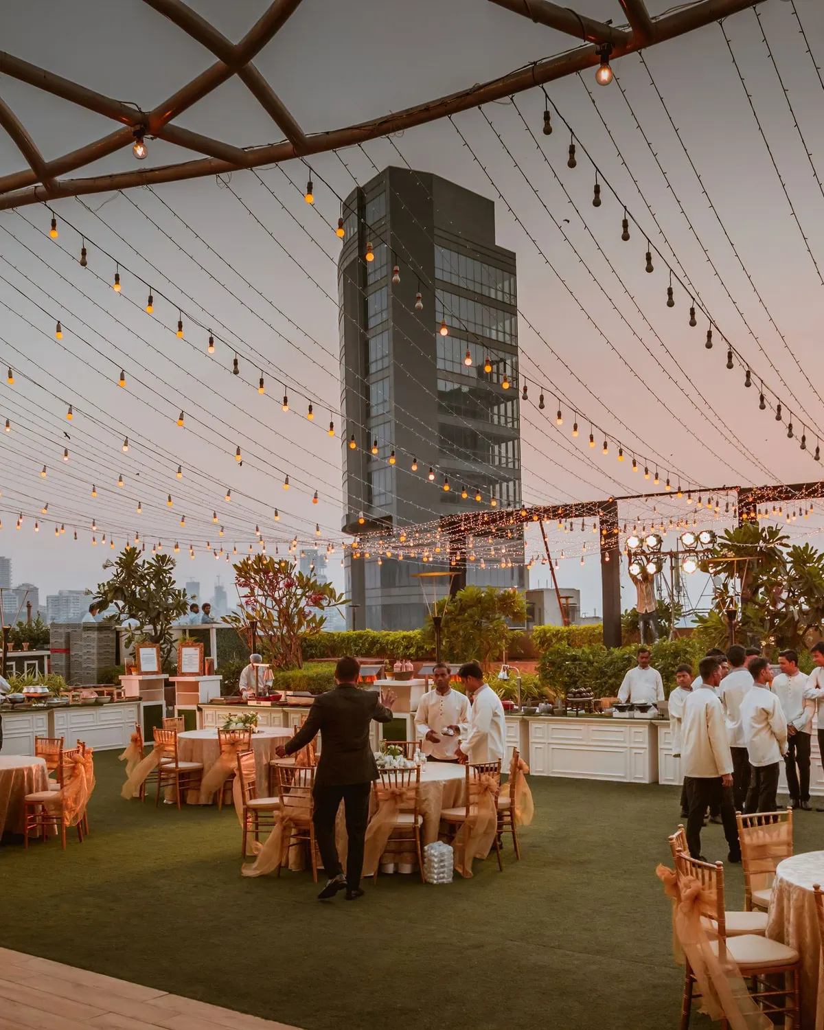 Temporary concept image of open-air evening gathering with long tables and warm lights at sunset; not property photography.