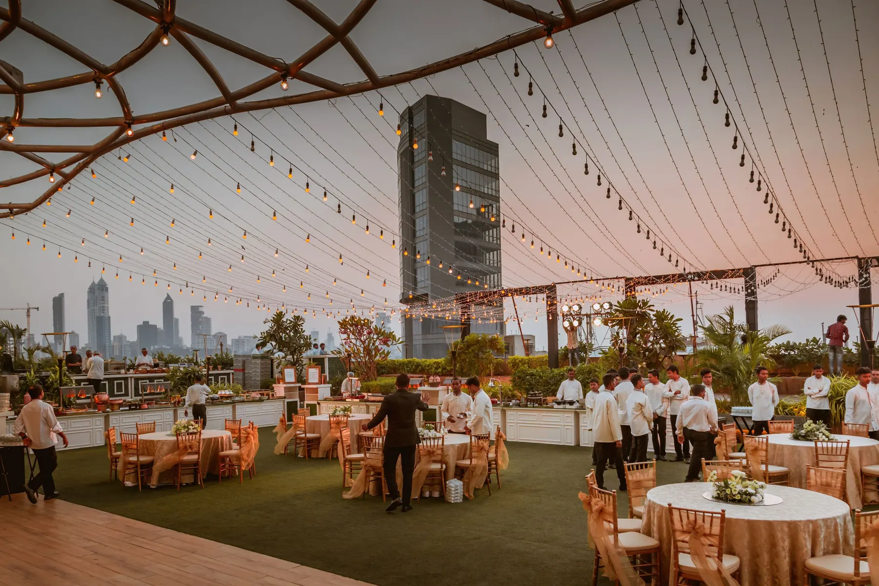 Temporary concept image of open-air evening gathering with long tables and warm lights at sunset; not property photography.