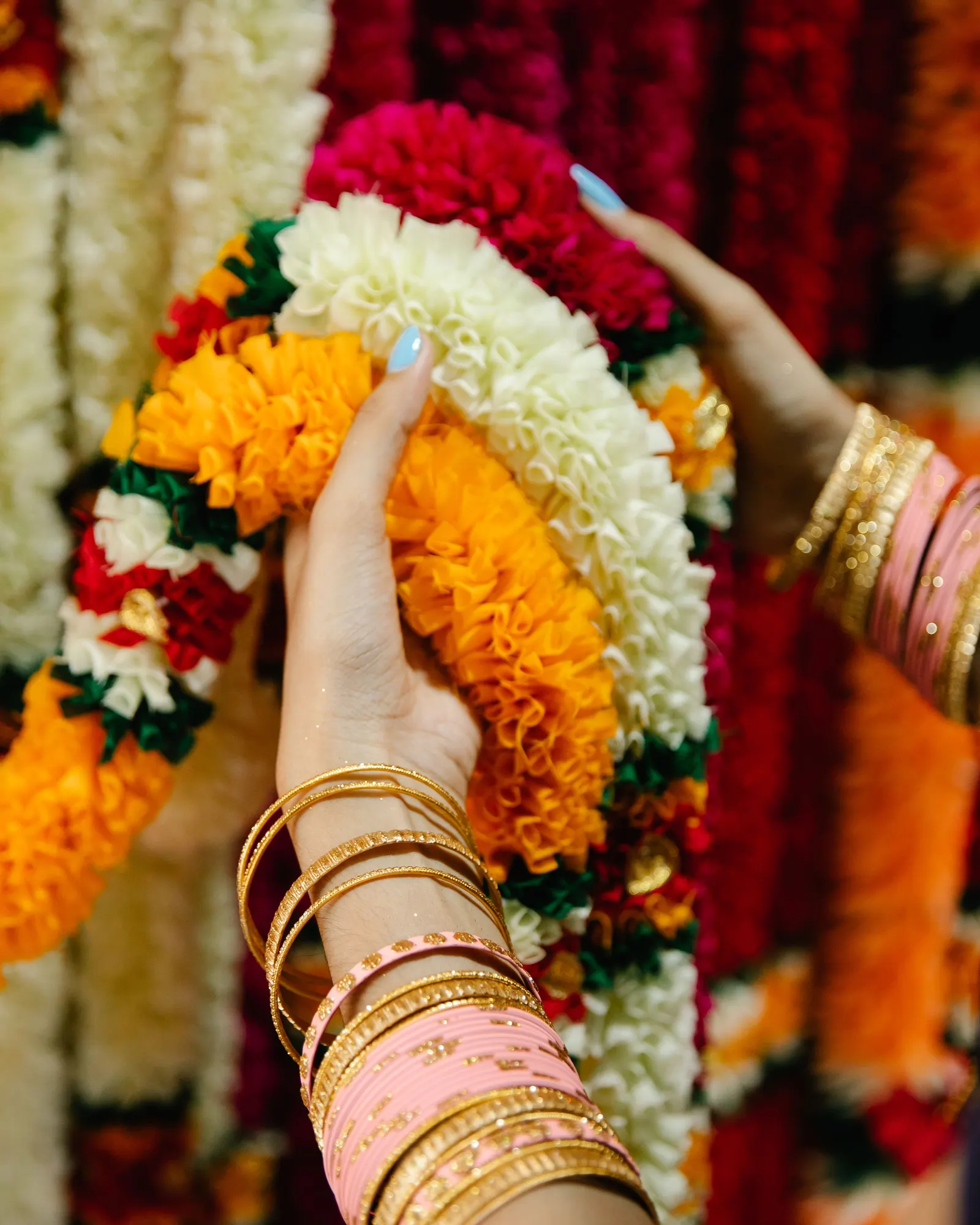 Temporary concept image of hands with gold bangles holding fresh flower garlands; not property photography.