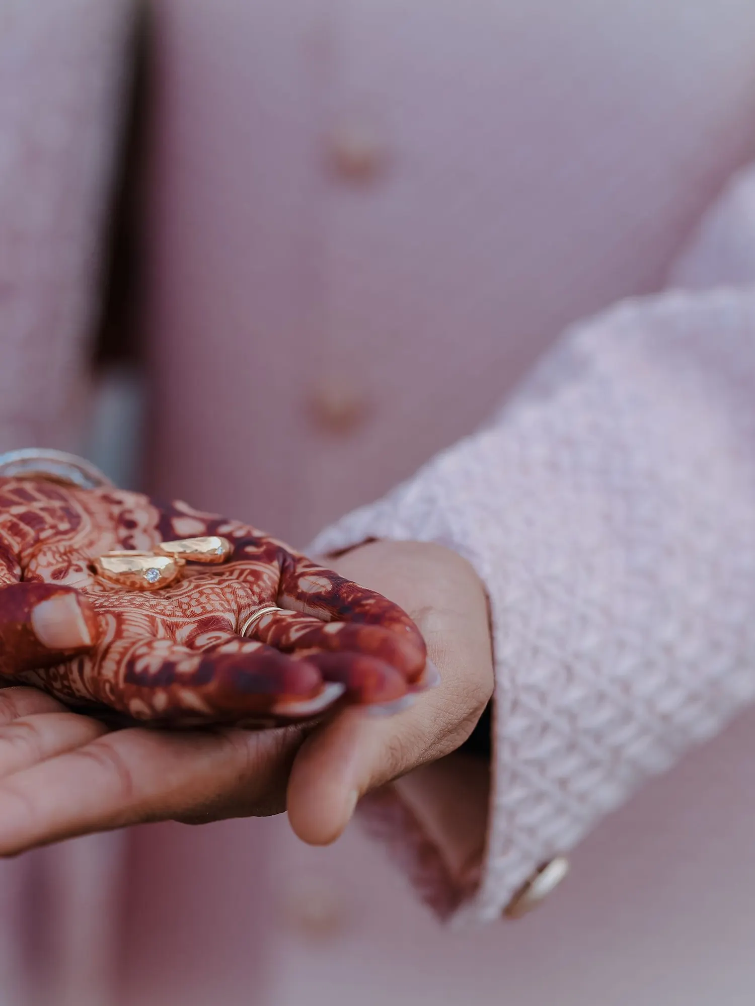 Temporary concept image of rings exchanged over henna-decorated hands at a ring ceremony; not property photography.