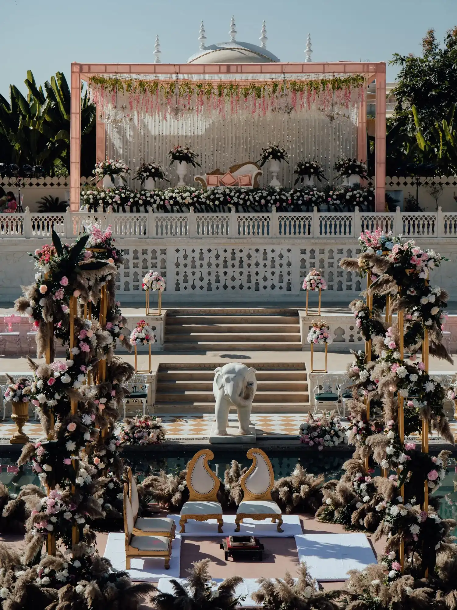 Temporary concept image of outdoor wedding setting with floral arrangements and draped seating; not property photography.