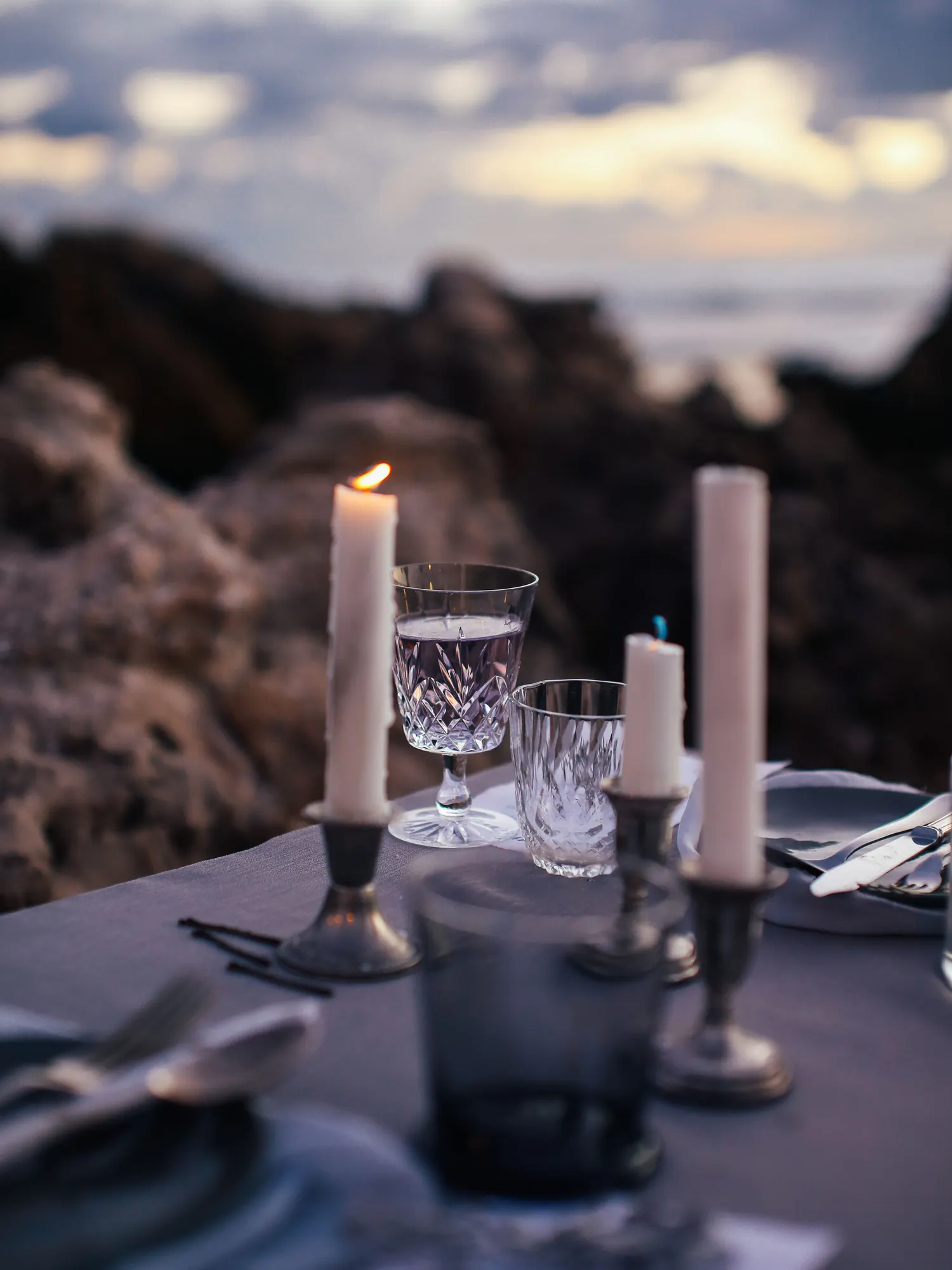 Temporary concept image of outdoor dinner table with candles set at sunset; not property photography.