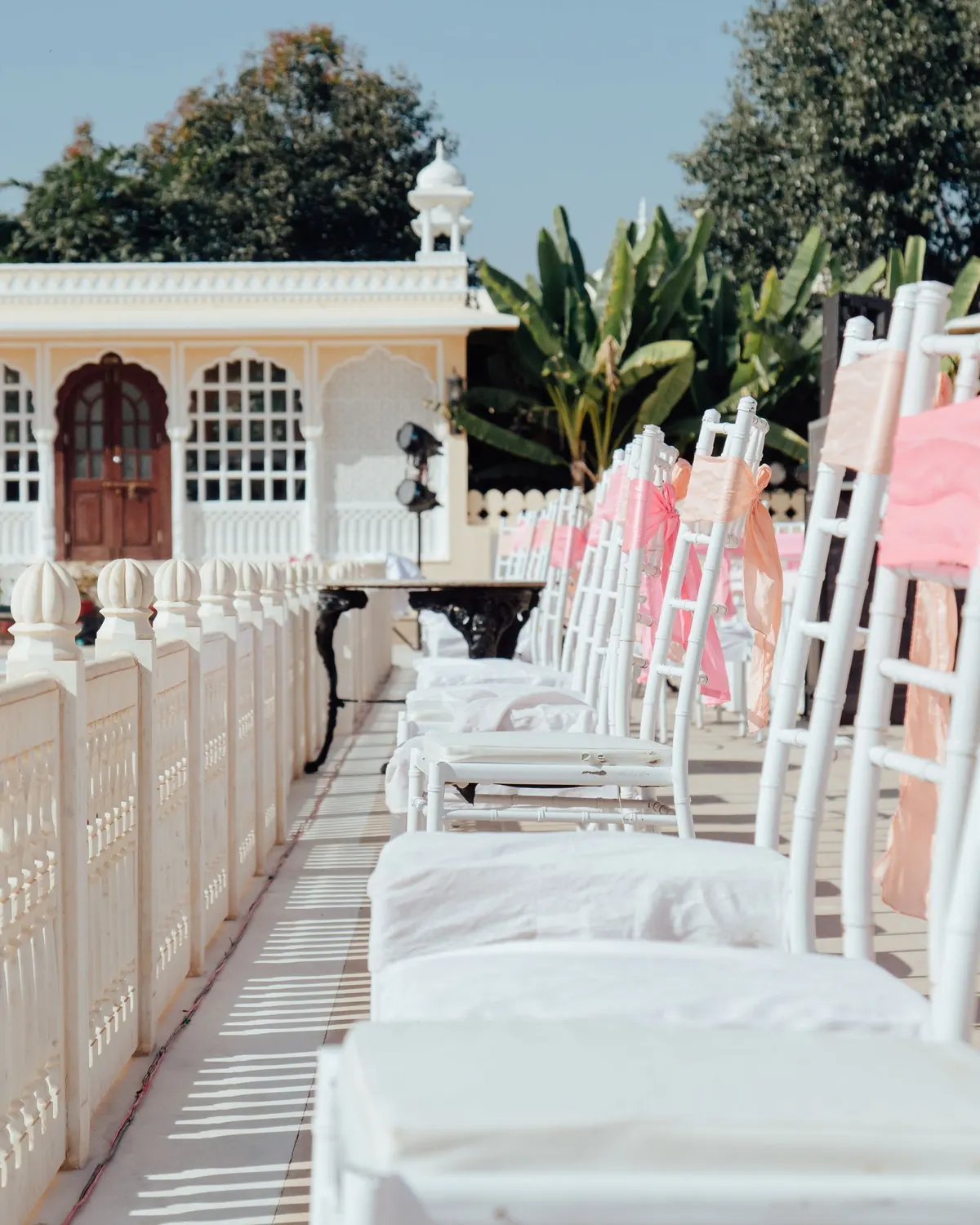Temporary concept image of outdoor wedding setting with white seating and pastel drapes; not property photography.