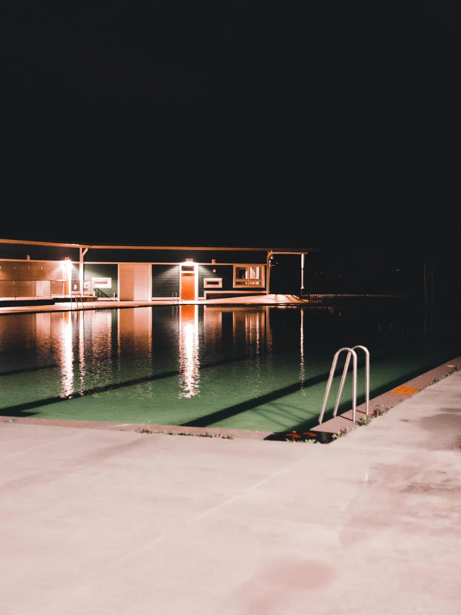 Temporary concept image of a pool reflecting warm architecture in the evening; not property photography.