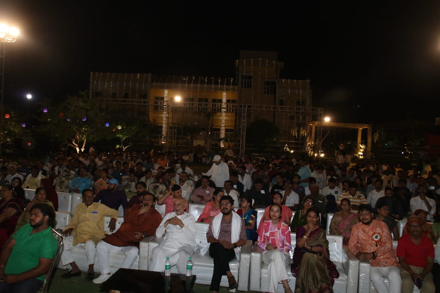 Audience seated outdoors during a festive event at Adarsh Vatika