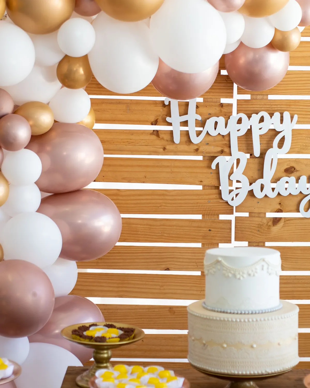 Temporary concept image of a birthday table with white cake, flowers and balloon décor; not property photography.