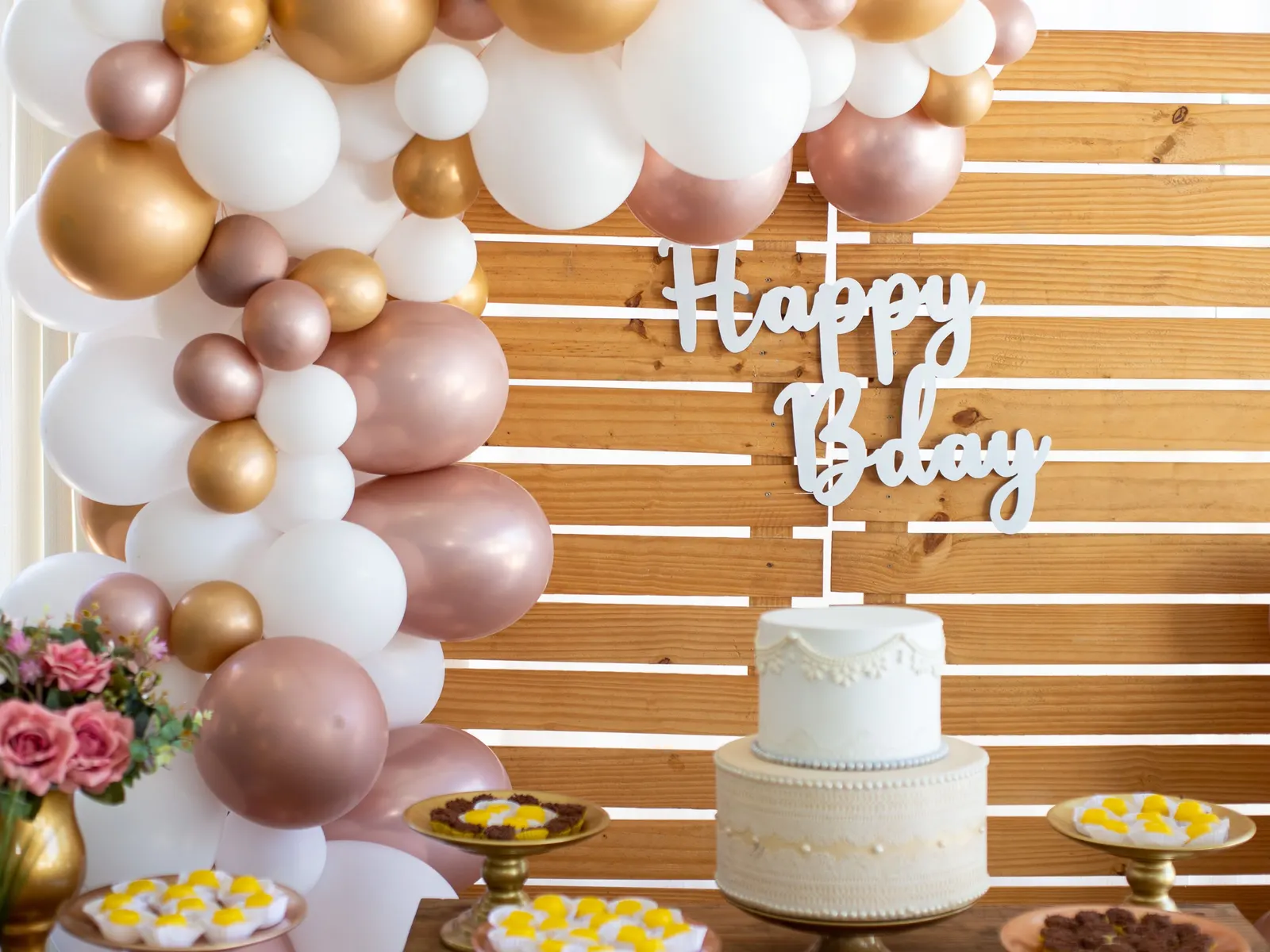 Temporary concept image of a birthday table with white cake, flowers and balloon décor; not property photography.