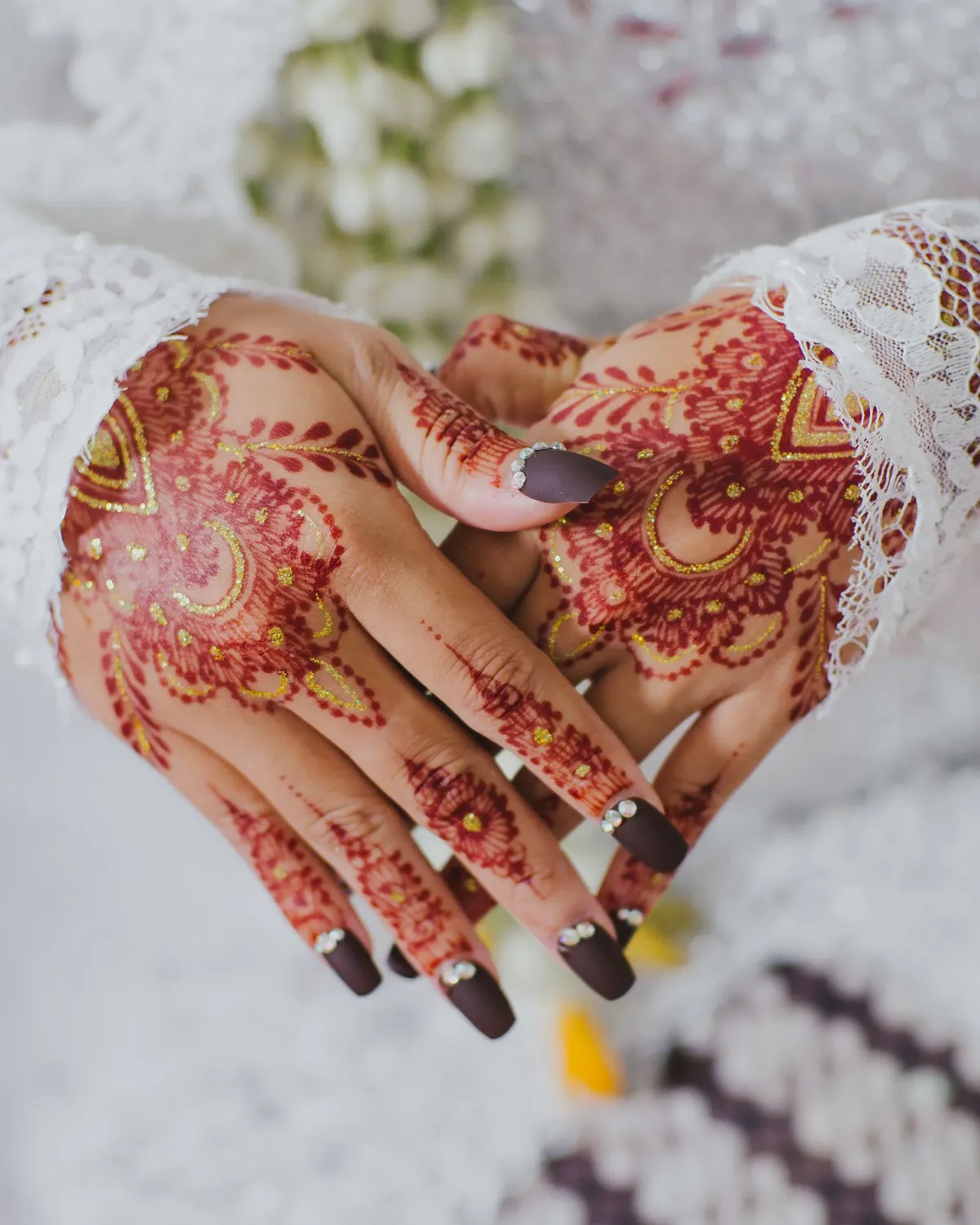 Temporary concept image of a bride's hands resting with fresh intricate mehendi; not property photography.