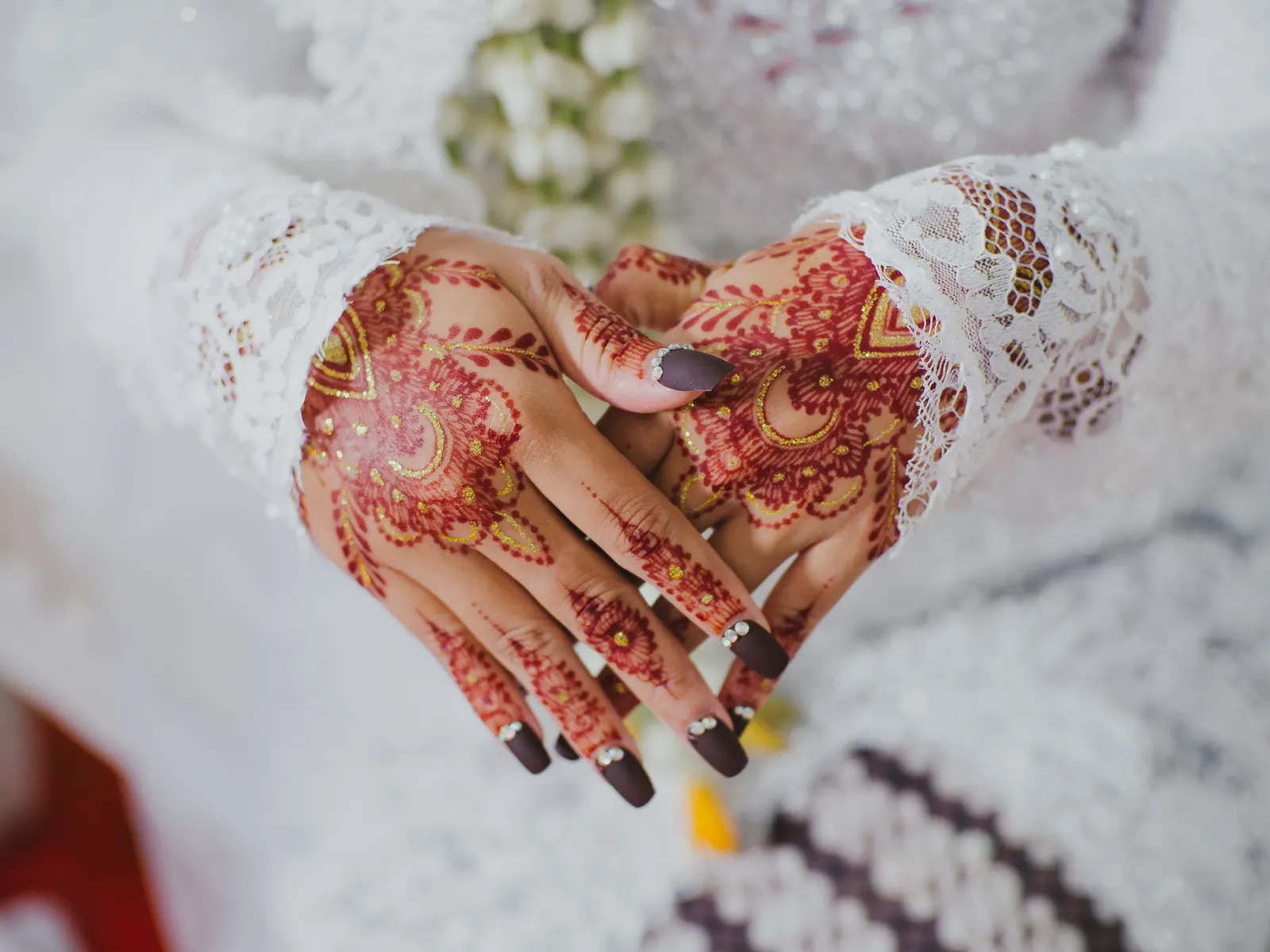 Temporary concept image of a bride's hands resting with fresh intricate mehendi; not property photography.