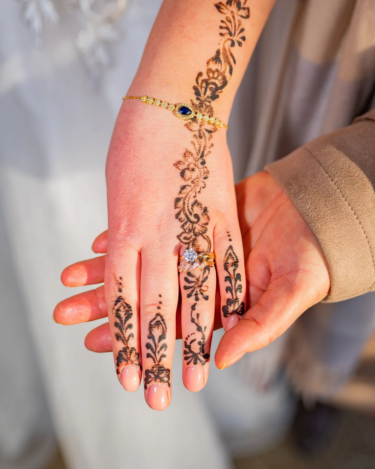 Temporary concept image of a bride's hand with intricate henna and delicate gold jewellery; not property photography.