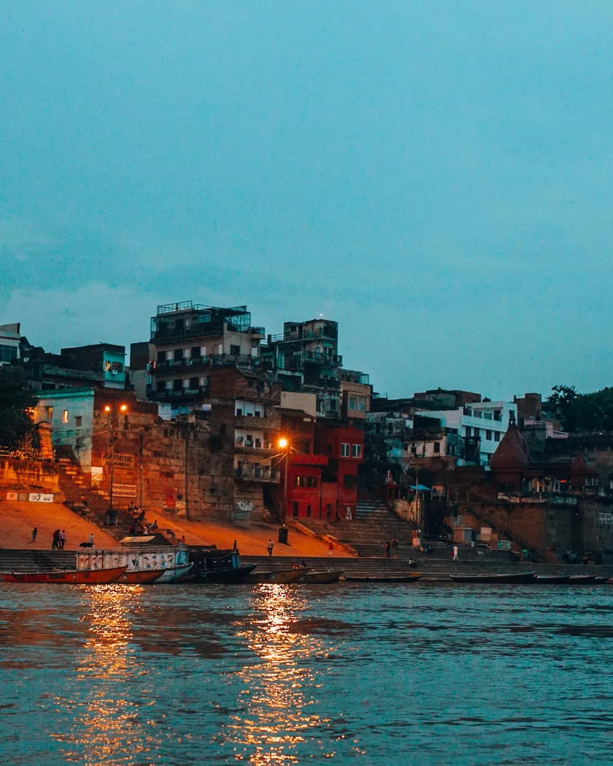 Temporary concept image of riverfront ghats glowing at twilight along the Ganga; not property photography.