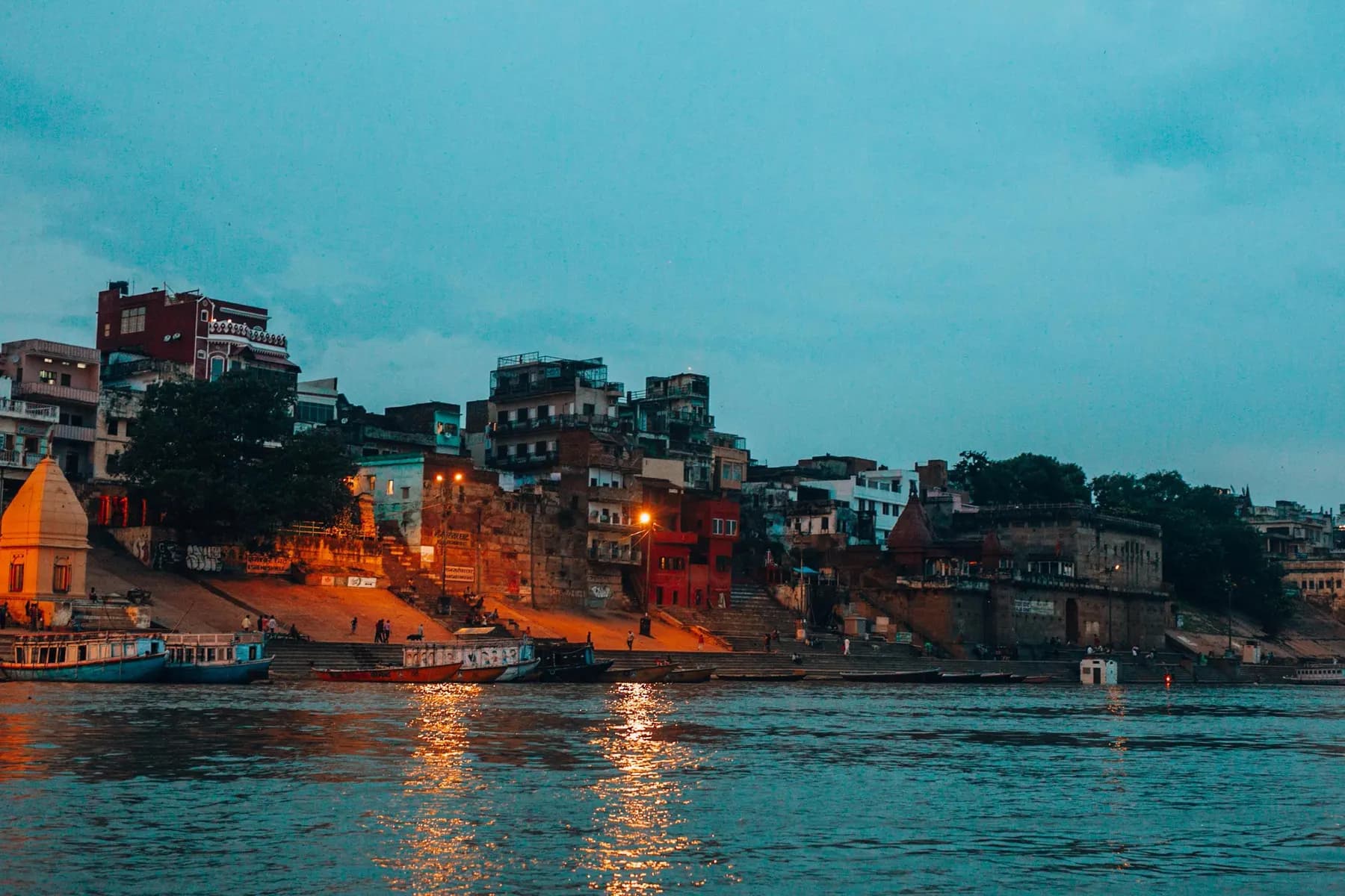 Temporary concept image of riverfront ghats glowing at twilight along the Ganga; not property photography.
