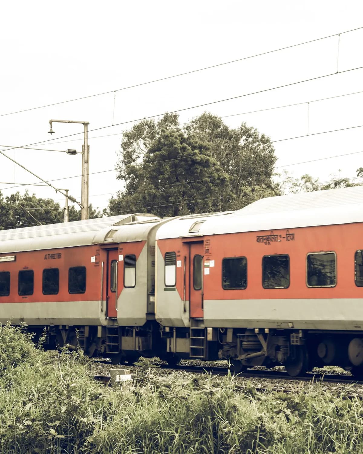 Temporary concept image of an Indian Railways train crossing green countryside; not property photography.