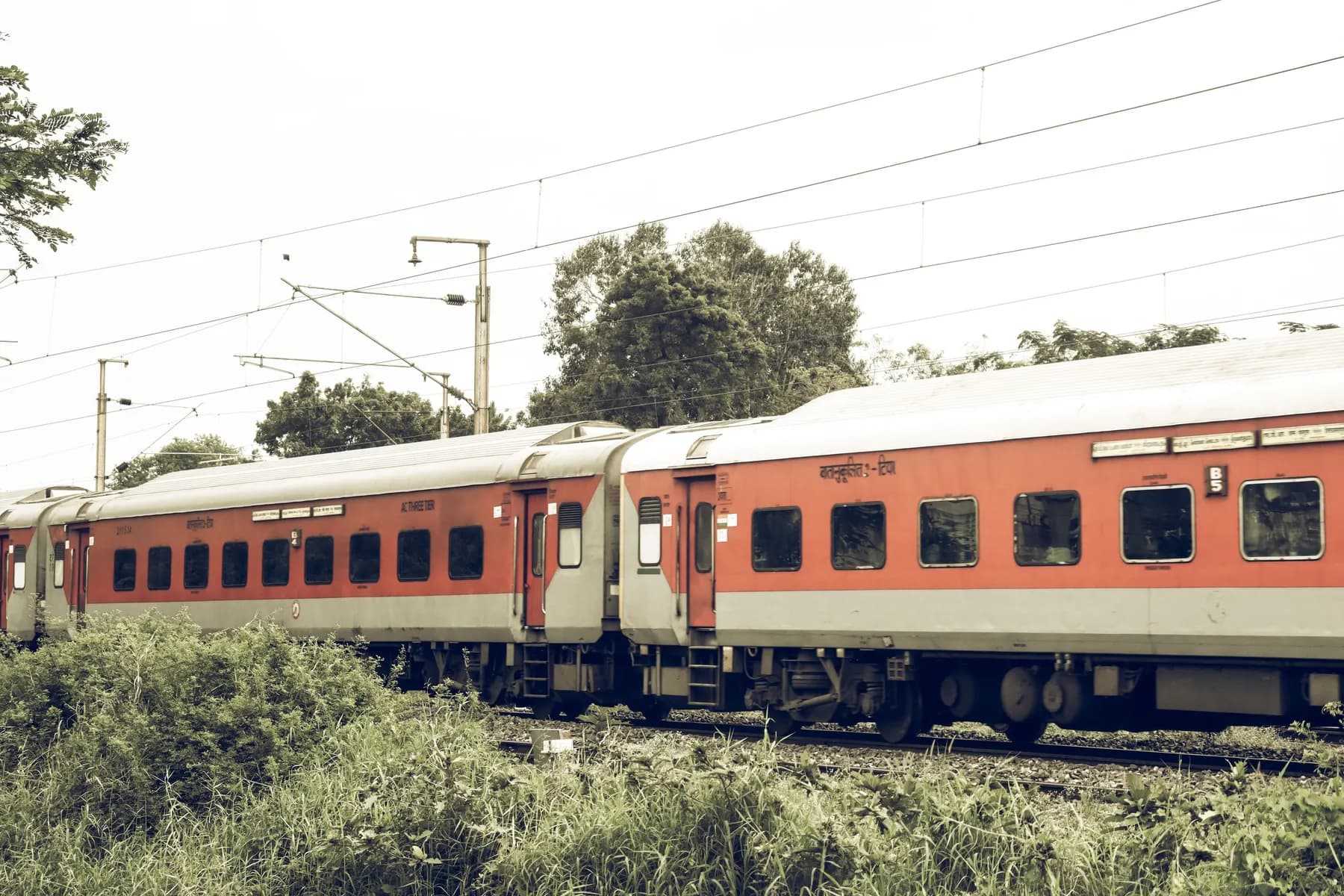 Temporary concept image of an Indian Railways train crossing green countryside; not property photography.
