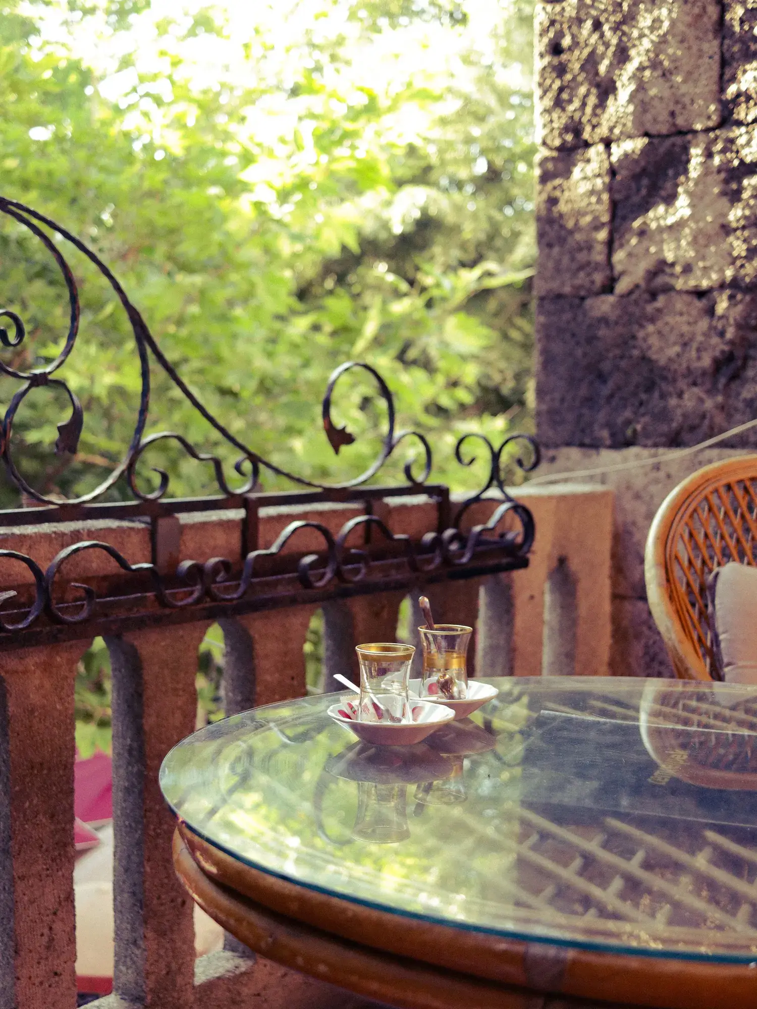 Temporary concept image of tea glasses on a quiet patio table overlooking greenery; not property photography.
