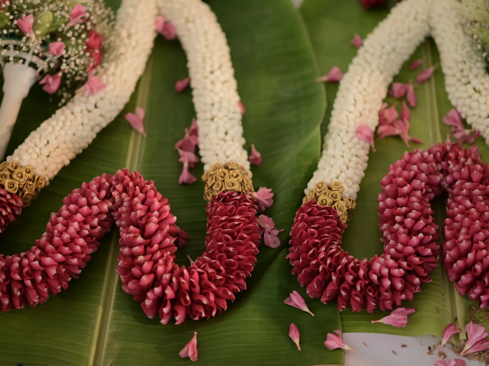 Temporary concept image of fresh flower garlands laid out on banana leaves for décor work; not property photography.