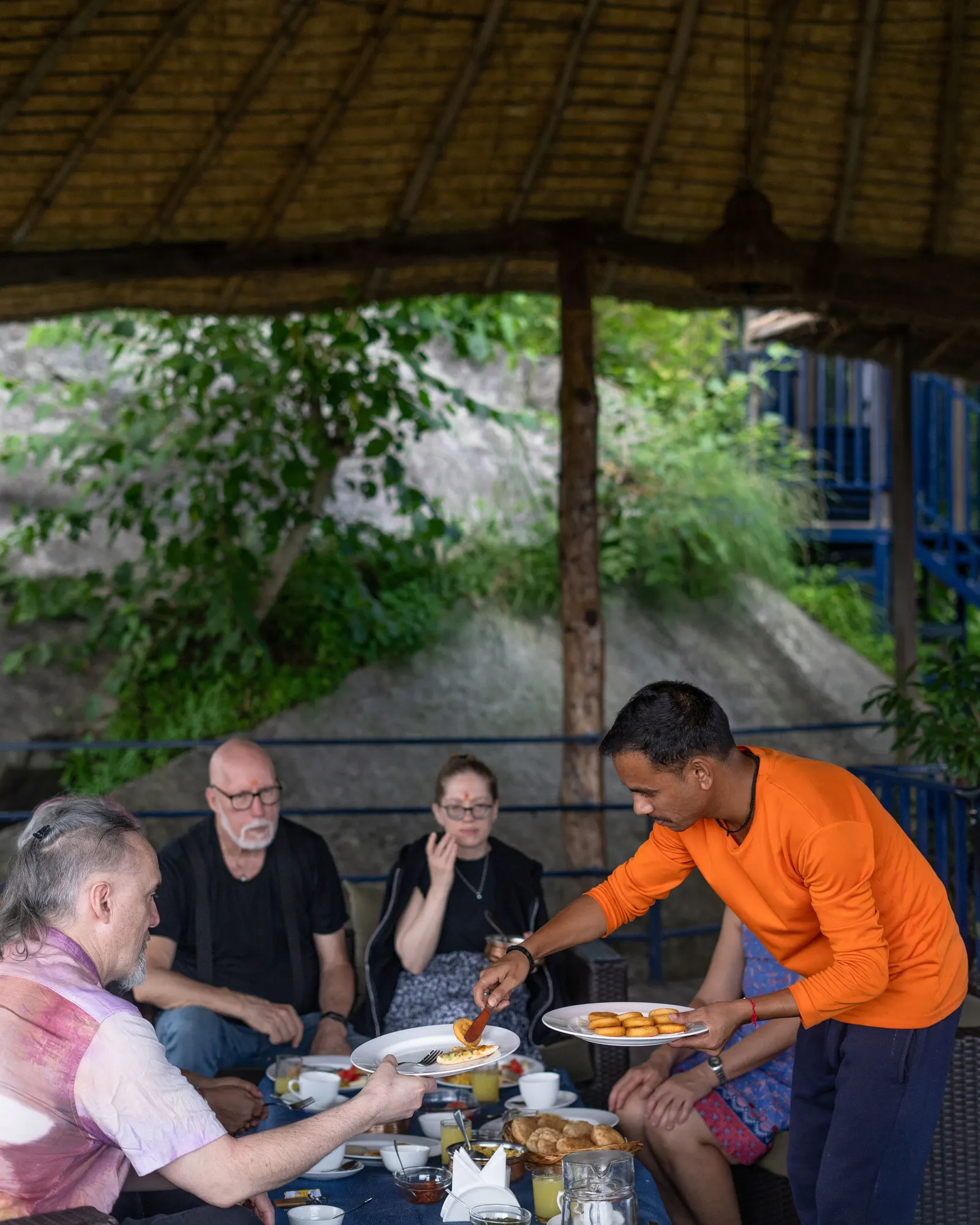 Temporary concept image of guests sharing an unhurried outdoor breakfast in garden shade; not property photography.