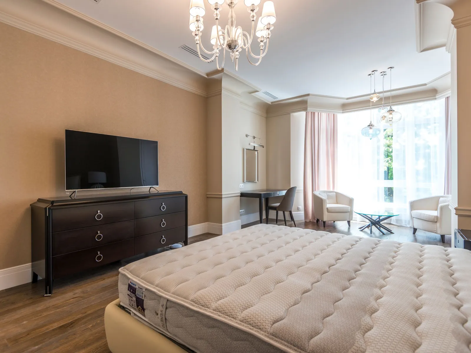 Temporary concept image of spacious bedroom with upholstered headboard and a soft chandelier; not property photography.