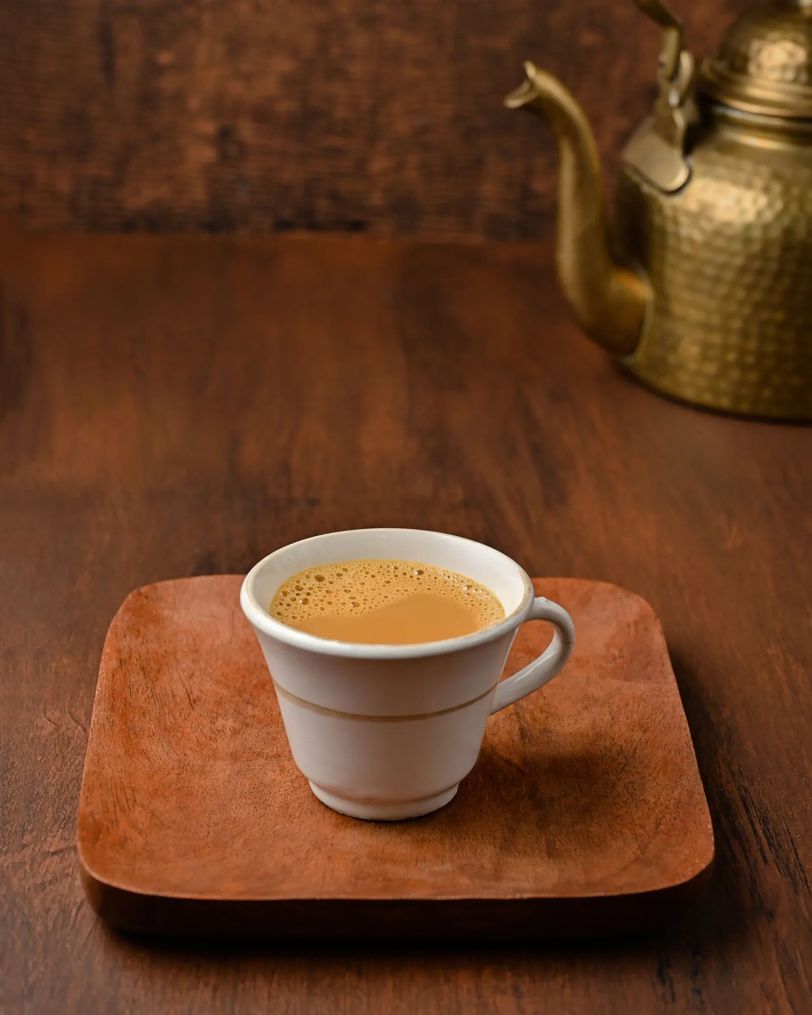Temporary concept image of morning tea served on a wooden tray beside a brass kettle; not property photography.