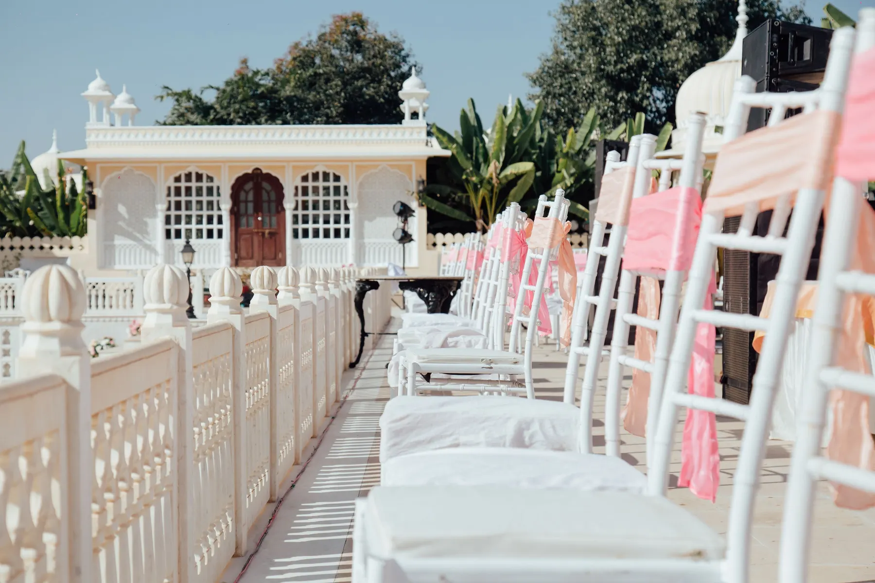 Temporary concept image of outdoor wedding setting with white seating and pastel drapes; not property photography.