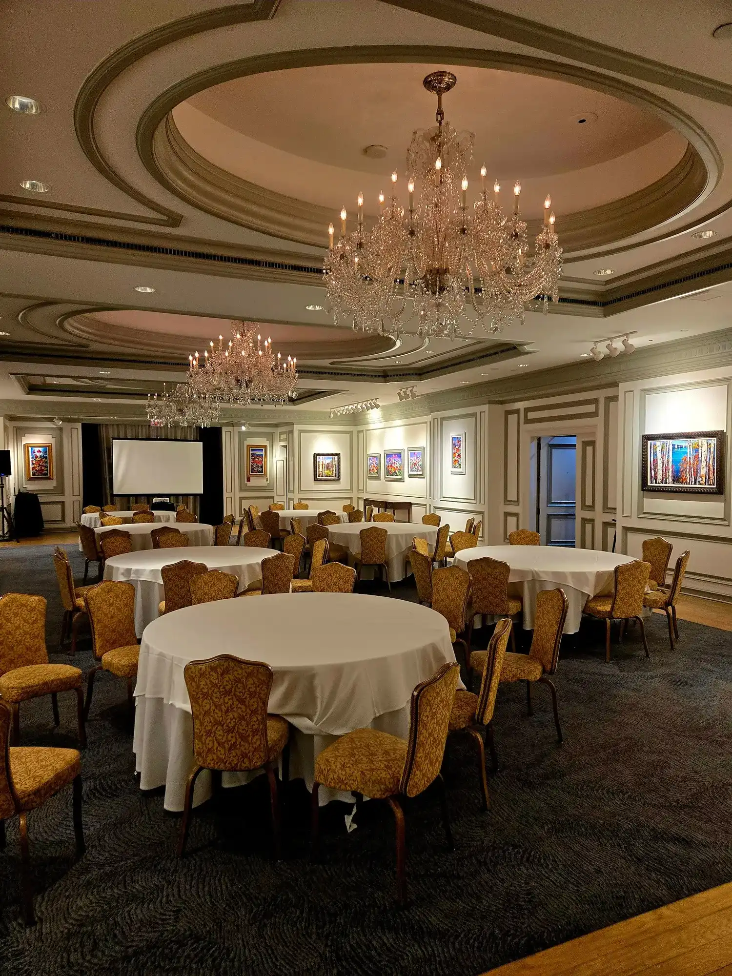 Temporary concept image of banquet hall with chandeliers and round tables prepared for an event; not property photography.